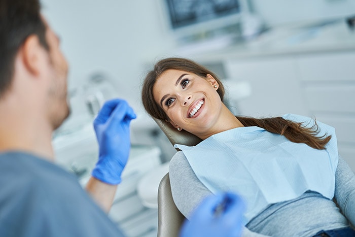 Woman smiling at doctor from reclining chair after receiving Botox treatment