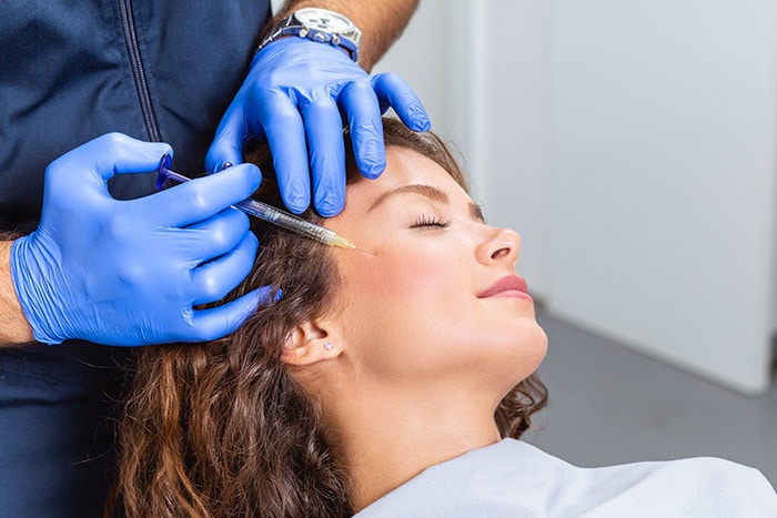 Doctor administering Botox injection to a woman's cheek in a clinical setting