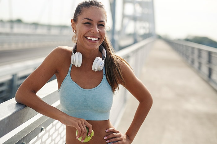 Woman in sports gear smiling and contemplating exercise