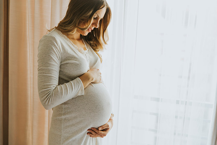 Pregnant woman gently touching her belly – Profhilo Structura is not recommended during pregnancy.