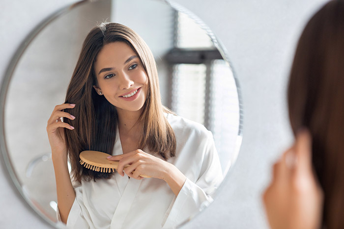 Woman examining her face – considering Profhilo Structura treatment for early signs of ageing.
