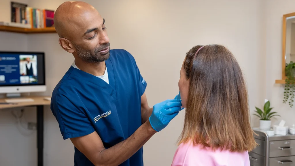 Dr Suresh Mohan assessing a patient's masseter muscle during a jaw consultation in Wimbledon